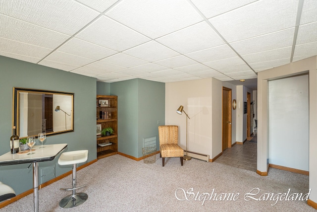 unfurnished room with a drop ceiling, light colored carpet, and a baseboard heating unit