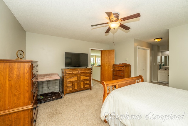 carpeted bedroom featuring a textured ceiling, connected bathroom, a closet, and ceiling fan