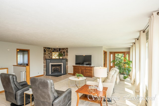 living room featuring a stone fireplace and light wood-type flooring