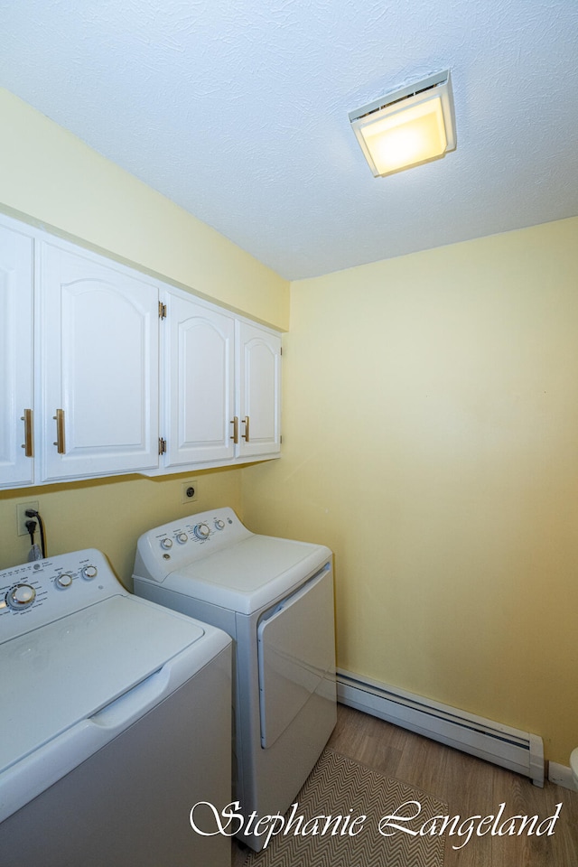 laundry room with washing machine and clothes dryer, cabinets, dark wood-type flooring, and a baseboard radiator