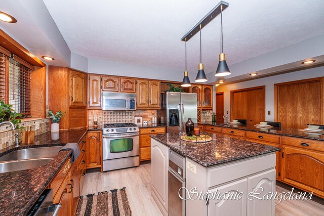 7300 Packer Dr NE, Belmont, MI 49306 - kitchen with stainless steel appliances, a sink, brown cabinetry, tasteful backsplash, and recessed lighting