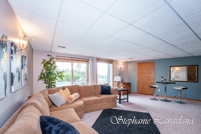 living room with a drop ceiling and light colored carpet