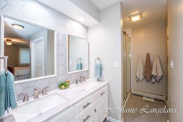 7300 Packer Dr NE, Belmont, MI 49306 - ensuite bathroom featuring baseboard heating, double vanity, ceiling fan, tasteful backsplash, and a shower stall