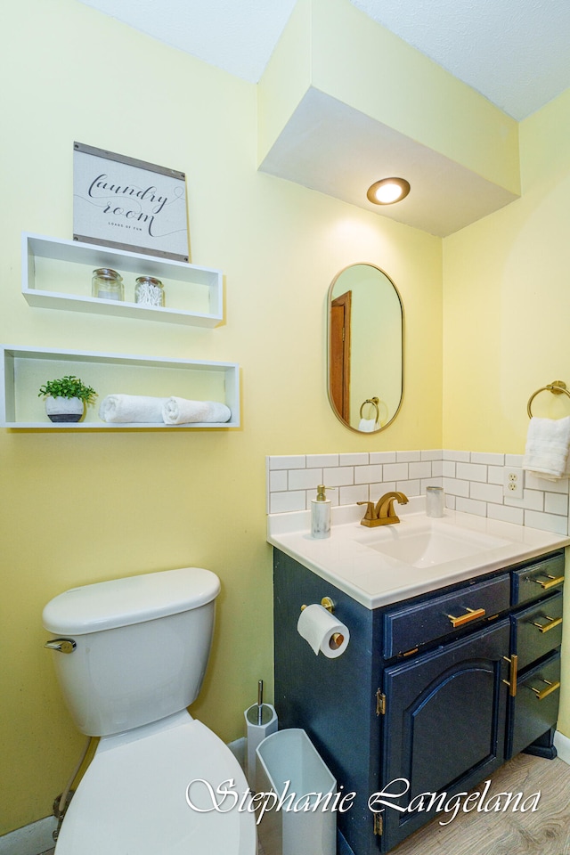 bathroom with vanity, toilet, and backsplash