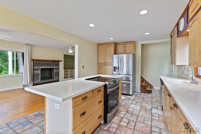 kitchen with ceiling fan, a center island, sink, stainless steel appliances, and light brown cabinetry