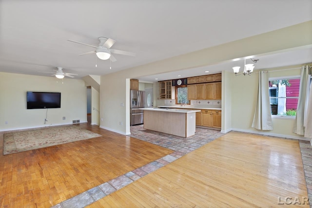 kitchen with a center island, stainless steel fridge with ice dispenser, decorative light fixtures, ceiling fan with notable chandelier, and light wood-type flooring