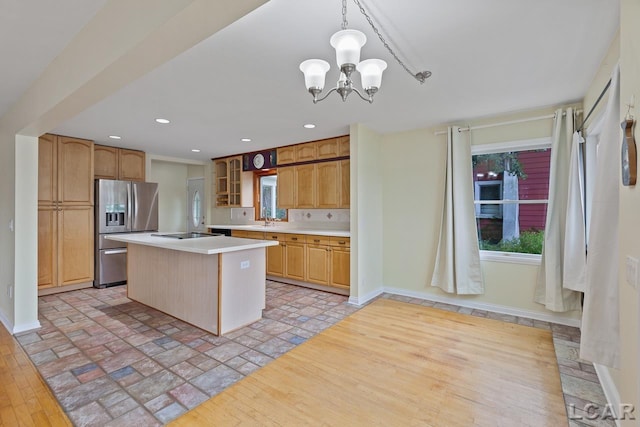 kitchen featuring stainless steel fridge, sink, decorative light fixtures, a chandelier, and a center island