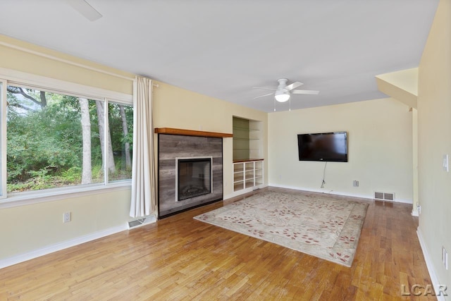 unfurnished living room with hardwood / wood-style floors, built in features, and ceiling fan