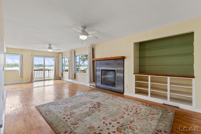 unfurnished living room featuring hardwood / wood-style floors, built in features, and ceiling fan