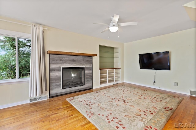 living room featuring wood-type flooring, built in features, and ceiling fan