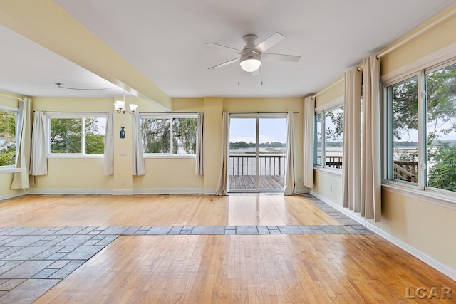 unfurnished sunroom with plenty of natural light and ceiling fan with notable chandelier