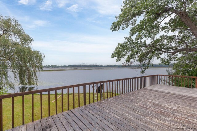 wooden terrace with a water view and a lawn