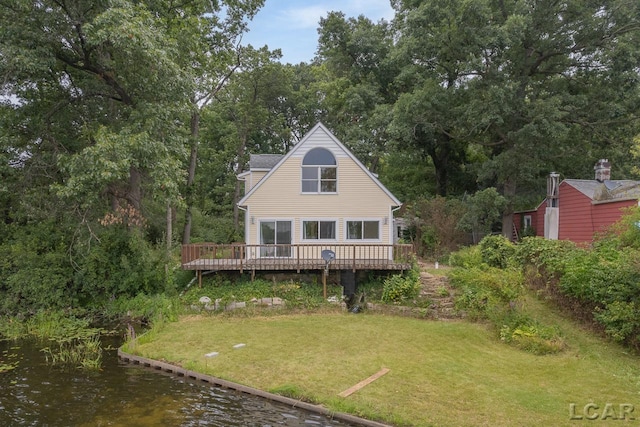 rear view of house with a lawn and a deck with water view