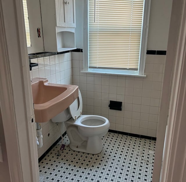 bathroom with toilet, tile patterned flooring, and tile walls