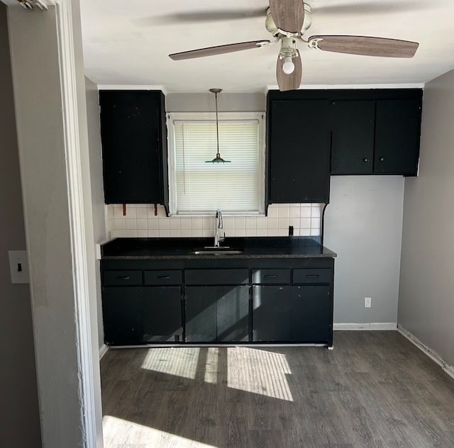 kitchen with dark wood-type flooring, decorative light fixtures, sink, and backsplash