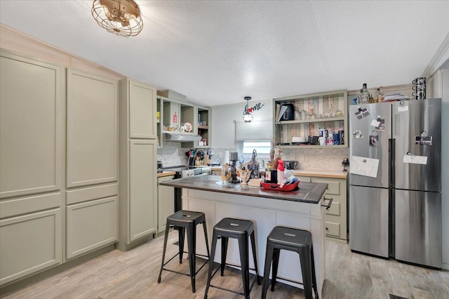 kitchen with a kitchen island, a kitchen bar, stainless steel appliances, and light hardwood / wood-style flooring