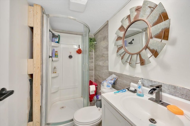 bathroom with a textured ceiling, vanity, an enclosed shower, and toilet