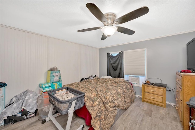 bedroom featuring cooling unit, light hardwood / wood-style flooring, ceiling fan, and ornamental molding