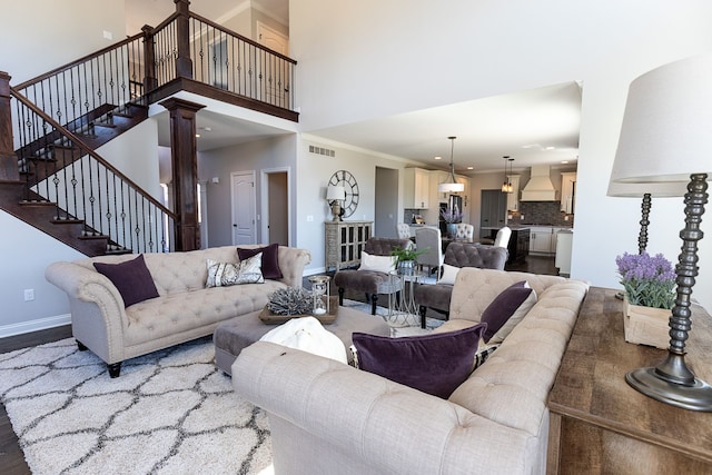 living room with a towering ceiling, hardwood / wood-style flooring, ornate columns, and crown molding