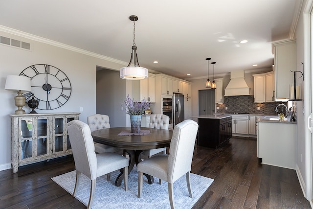 dining room with crown molding, sink, and dark hardwood / wood-style floors