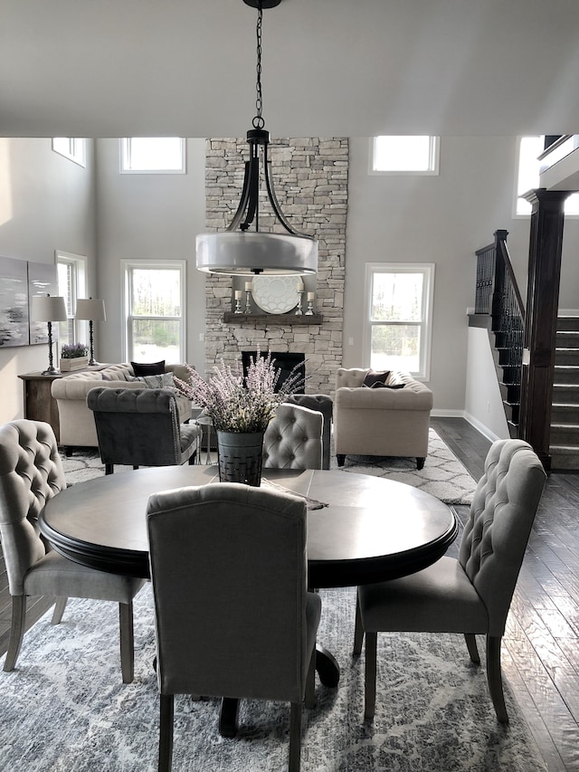 dining space with hardwood / wood-style floors, a healthy amount of sunlight, a towering ceiling, and a fireplace