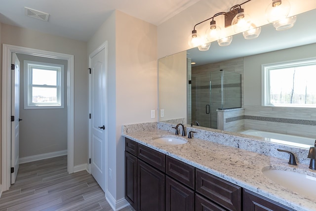 bathroom featuring plus walk in shower, vanity, and a wealth of natural light