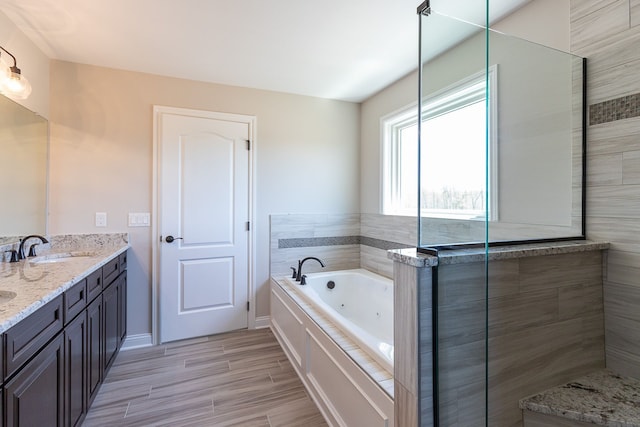 bathroom with vanity, a relaxing tiled tub, and hardwood / wood-style flooring