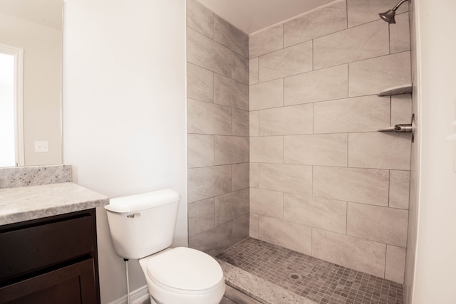 bathroom featuring a tile shower, vanity, and toilet