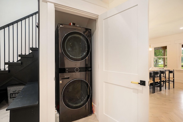 laundry room featuring light parquet flooring and stacked washer and clothes dryer