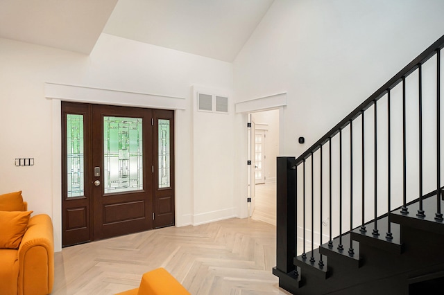 foyer entrance featuring light parquet flooring and high vaulted ceiling