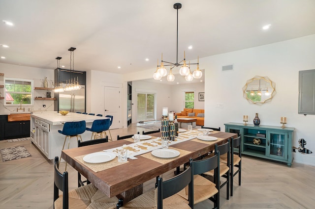 dining area featuring a chandelier, light parquet flooring, and sink