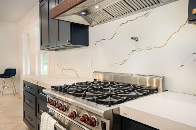 kitchen featuring light stone countertops, light parquet flooring, high end stainless steel range, and exhaust hood