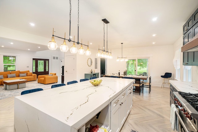 kitchen featuring decorative light fixtures, a center island, a wealth of natural light, and light parquet flooring