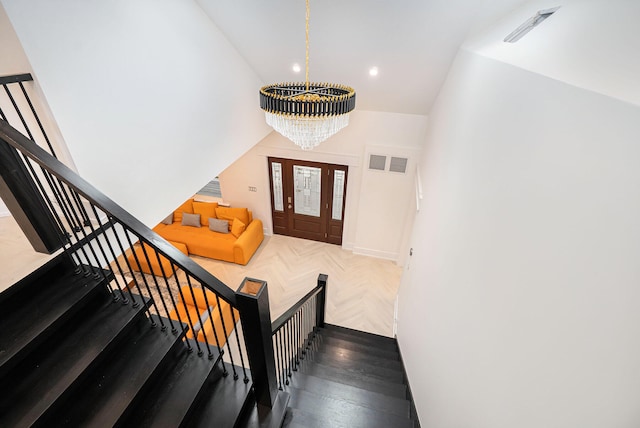 entrance foyer featuring lofted ceiling, dark parquet floors, and a notable chandelier