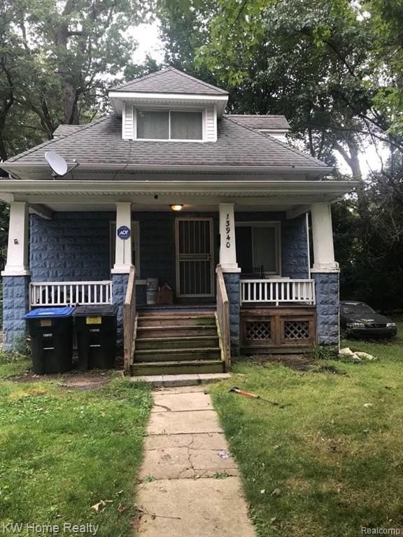 bungalow-style home featuring covered porch and a front lawn