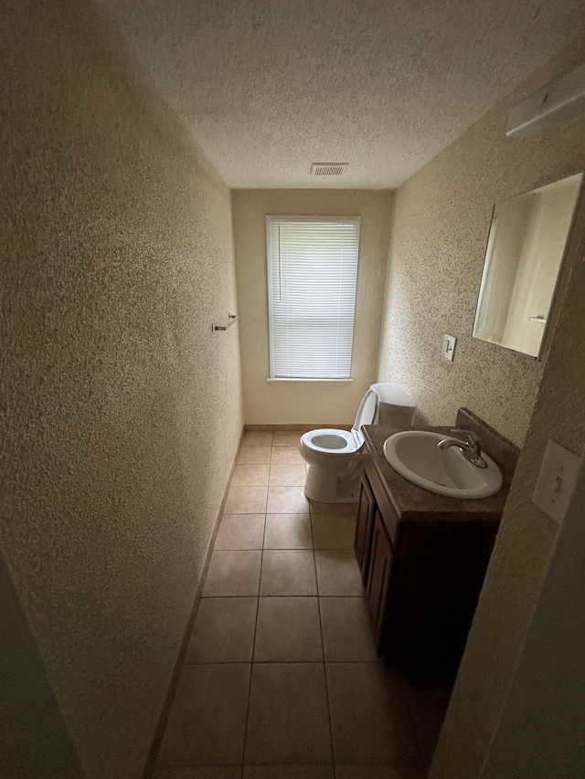 bathroom featuring tile patterned floors, vanity, toilet, and a textured ceiling