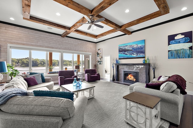 living room with beam ceiling, a water view, ceiling fan, and coffered ceiling