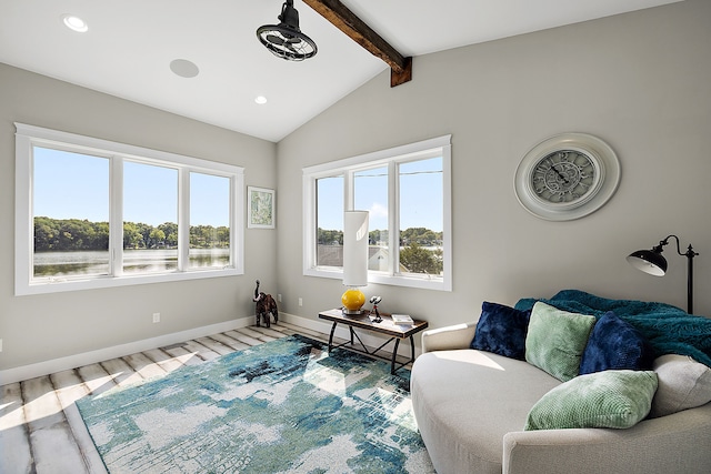 living room with vaulted ceiling with beams, a wealth of natural light, and light hardwood / wood-style flooring