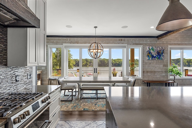 kitchen with light wood-type flooring, extractor fan, high end stainless steel range oven, a water view, and wood walls