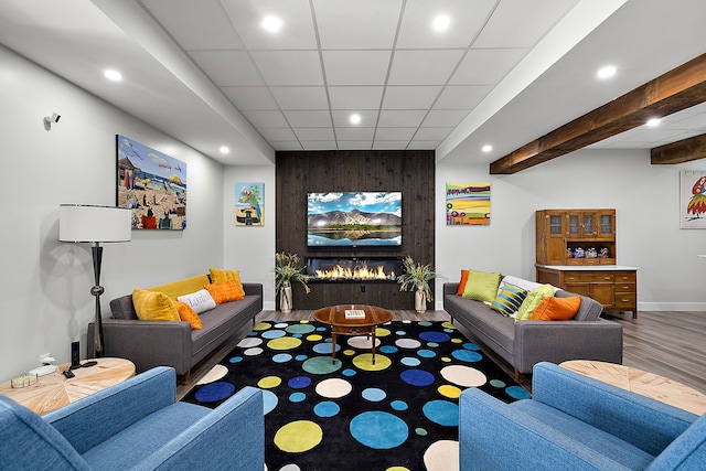 living room featuring wood-type flooring, a large fireplace, and a paneled ceiling