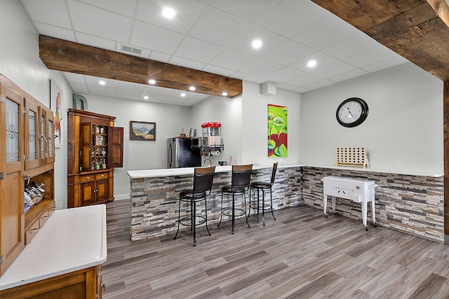 bar featuring stainless steel refrigerator and light hardwood / wood-style flooring