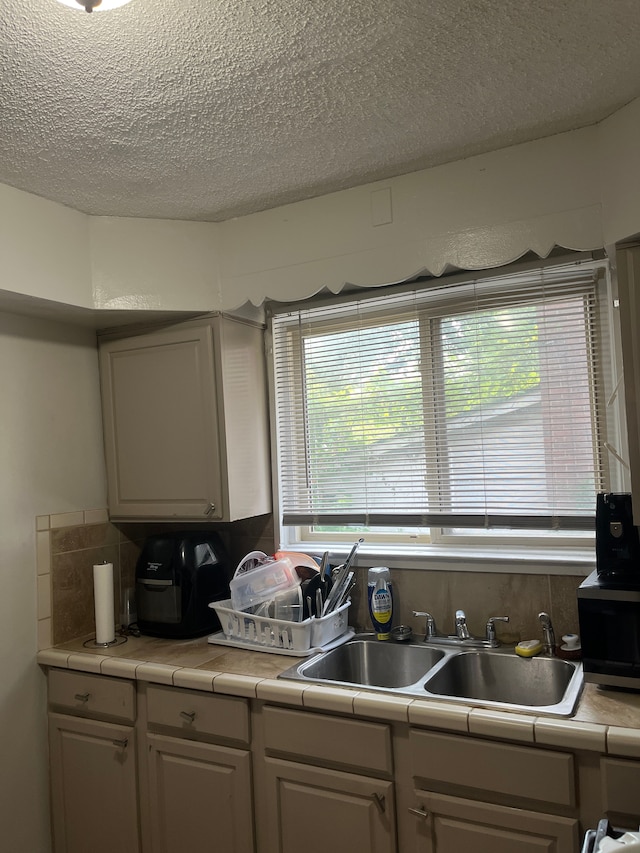 kitchen featuring tile countertops, sink, and a textured ceiling