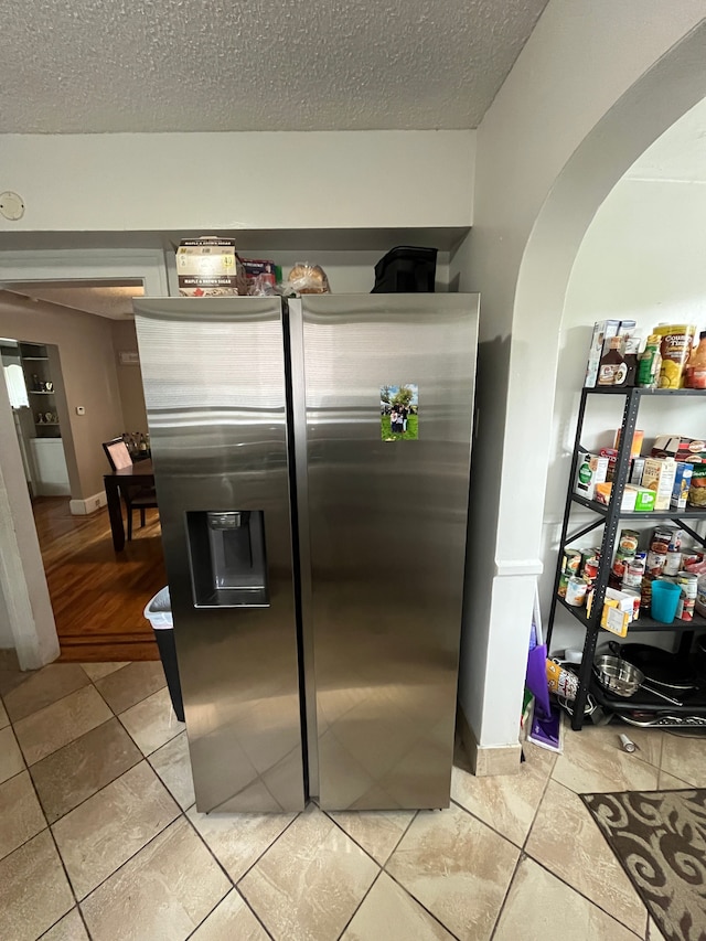 kitchen with a textured ceiling, stainless steel refrigerator with ice dispenser, and tile patterned floors