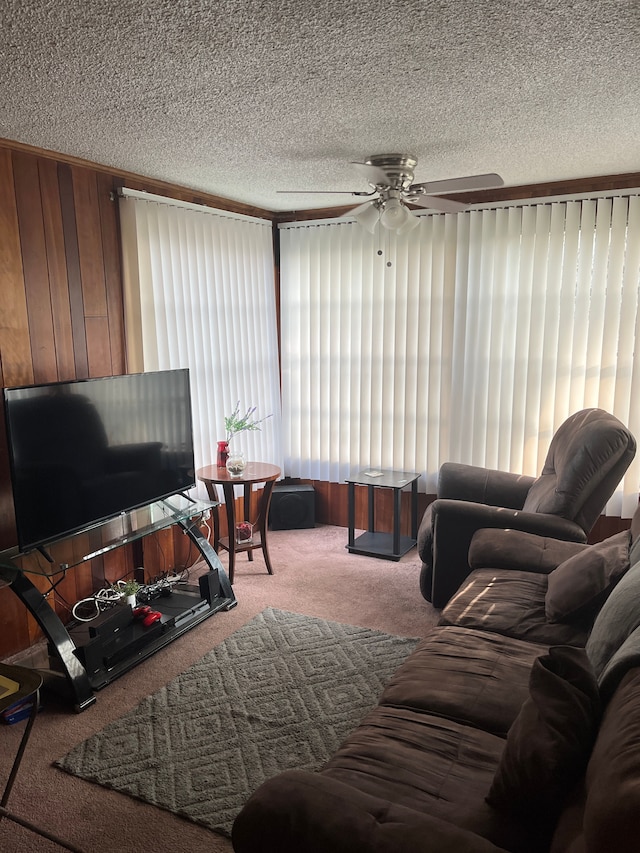 living room with light carpet, wooden walls, ceiling fan, and a textured ceiling