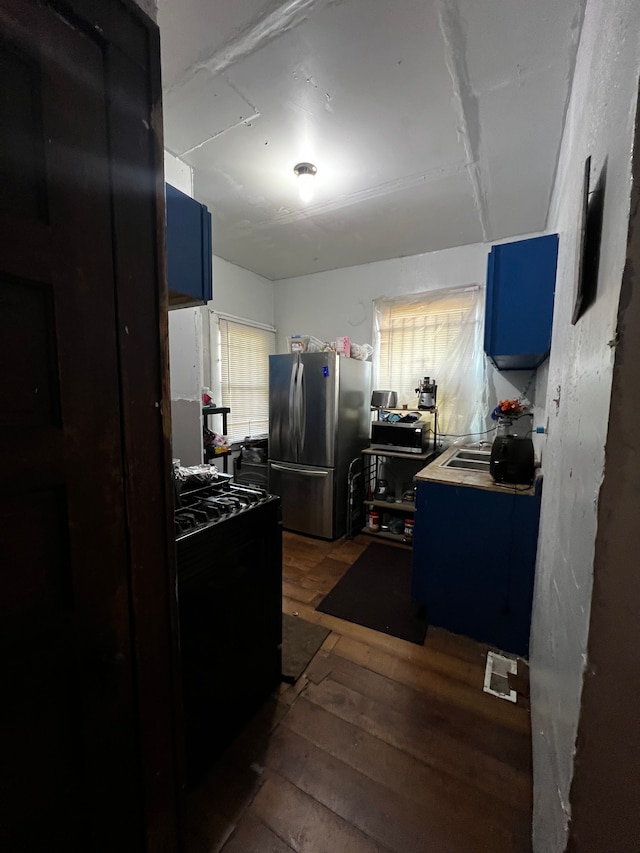 kitchen featuring black range, dark hardwood / wood-style floors, stainless steel fridge, and blue cabinets