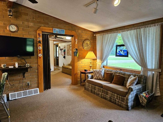 living room with carpet floors, brick wall, and lofted ceiling