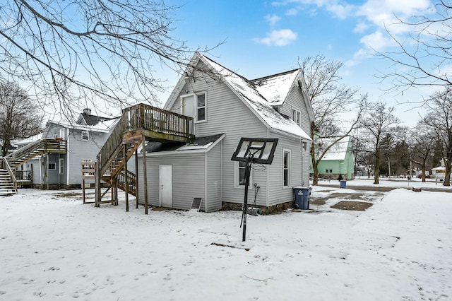 snow covered back of property featuring a wooden deck