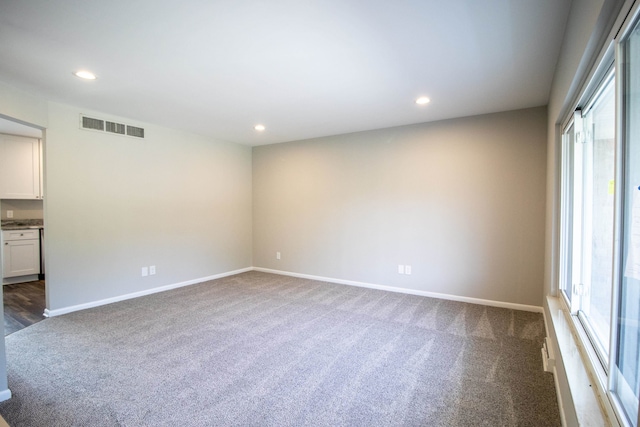 spare room featuring a healthy amount of sunlight and dark carpet