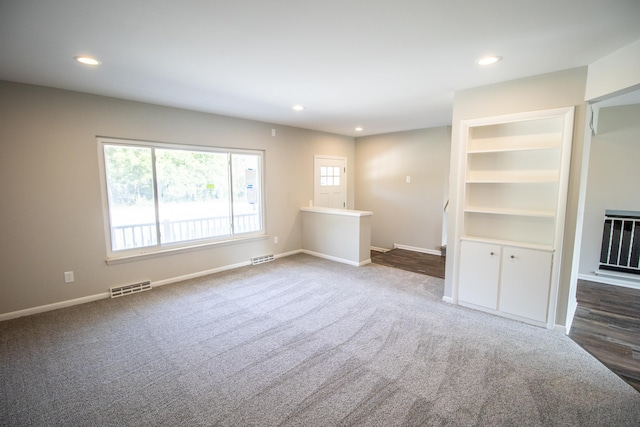 unfurnished living room with dark carpet