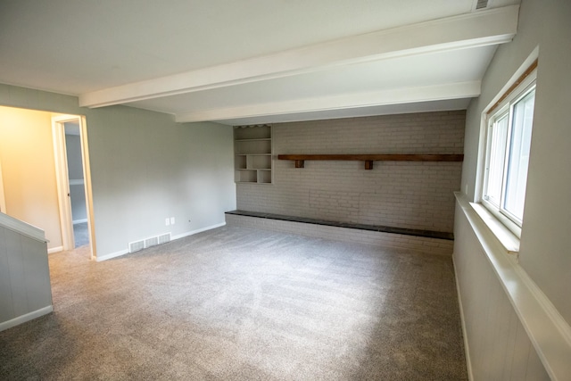 spare room with carpet flooring, beam ceiling, and brick wall